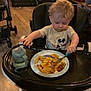 toddler, child, high_chair, pasta, fork, sippy_cup, mickey_mouse, curly_hair, indoor, wooden_floor, feeding, plate, baby, eating, clothing, person, food, tray, chair, stroller