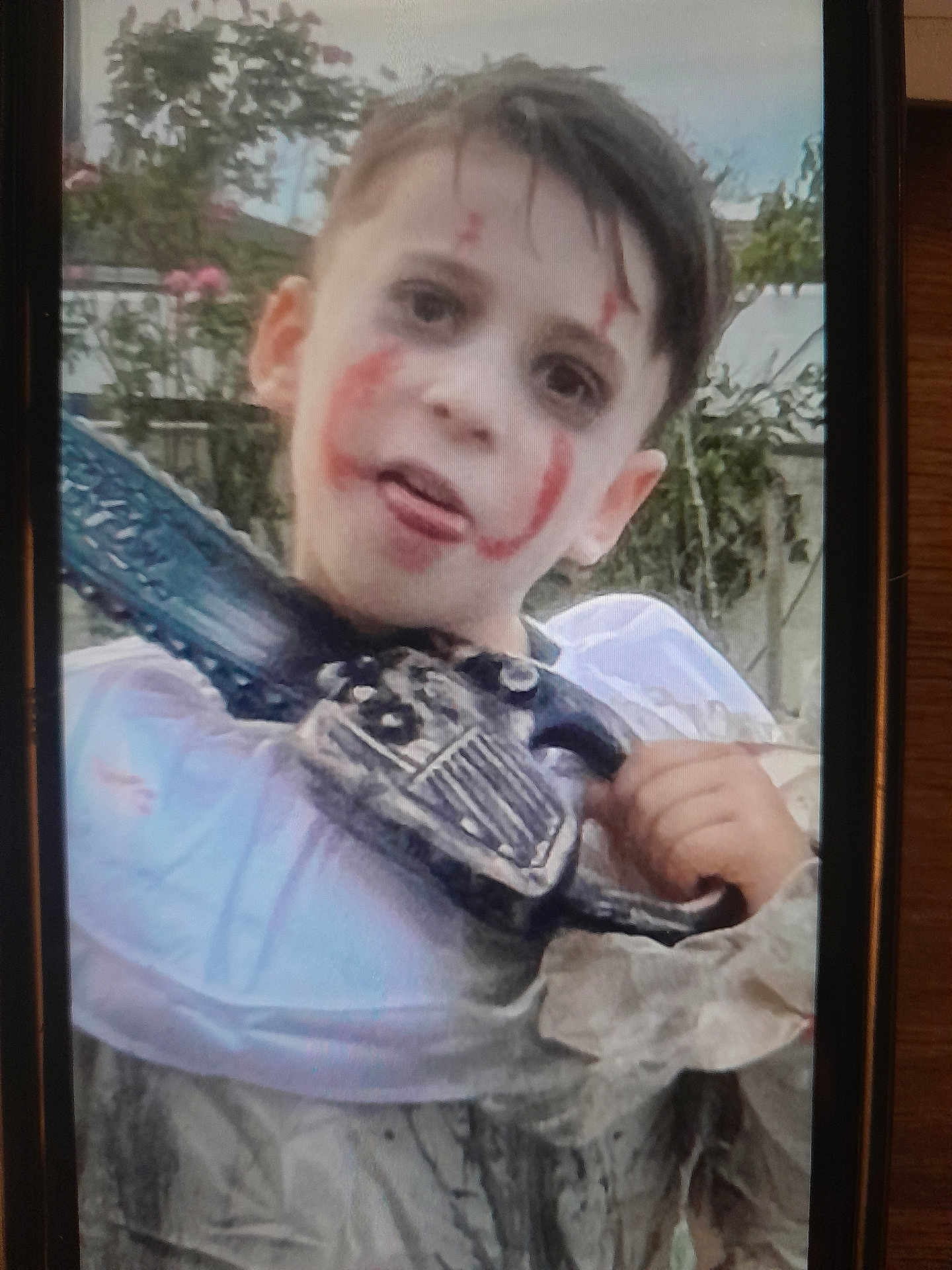 Clement a rejoint le concours — aidez-le/la à gagner de superbes lots ! child, face_paint, costume, chainsaw, toy, outdoor, garden, spooky, halloween, makeup, playful, smile, person, young, portrait, hand, hair, clothing, expression, daylight