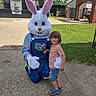 Kyler is registered to the contest to win money with this photo: child, person, costume, easter_bunny, face_paint, outdoor, grass, building, sidewalk, concession_stand, blue_overalls, striped_shirt, sandals, greenery, sky, brick_archway, smile, holiday, spring, event