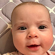 Rylan joined the competition — help win amazing prizes! baby, face, close_up, infant, expression, skin, eyes, mouth, cheeks, quilt, pattern, lying_down, pink_clothing, young_child, portrait, cute, adorable, indoor, child, person