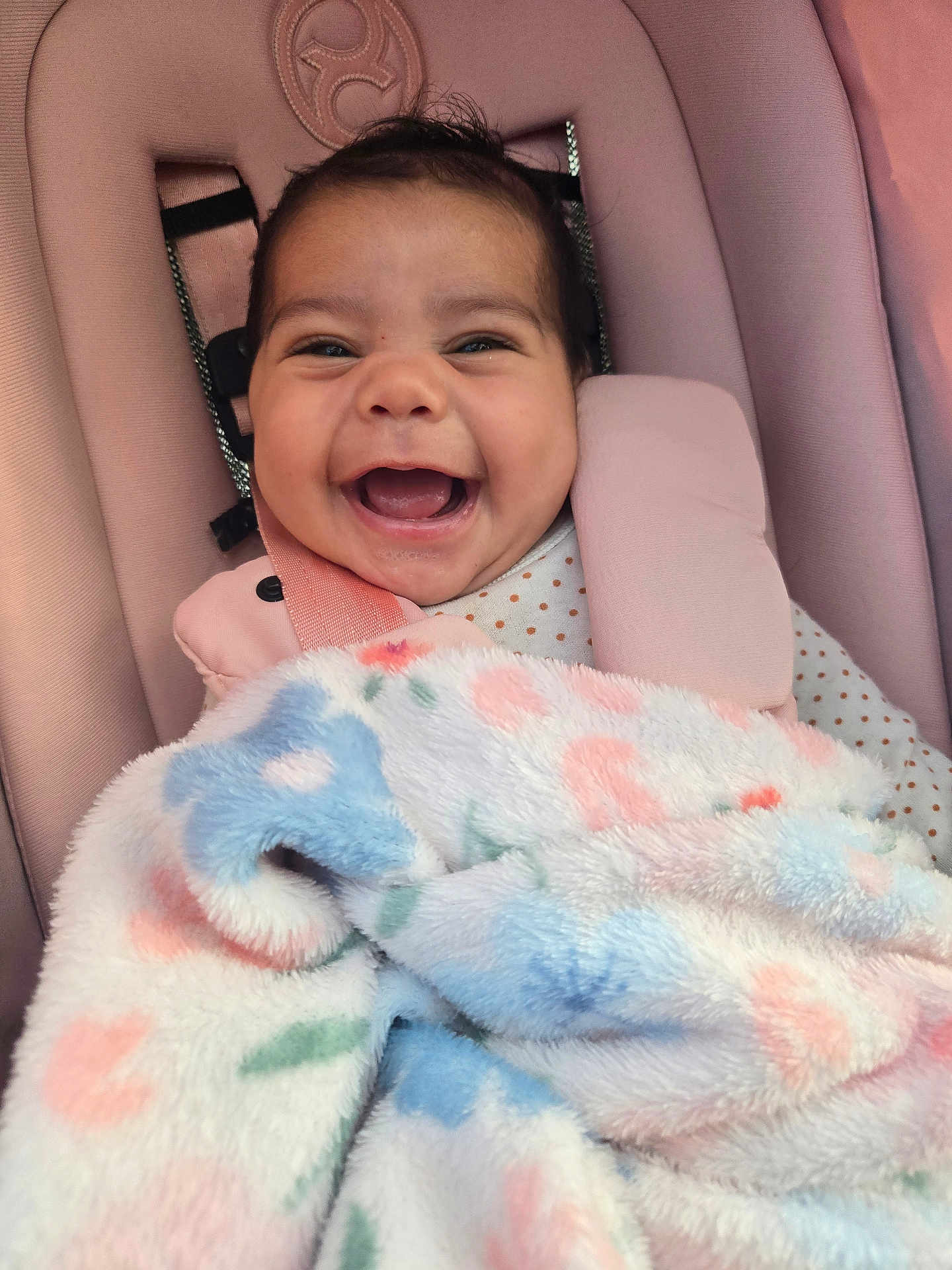 Natalia is registered to the contest to win money with this photo: baby, smile, blanket, car_seat, pink, happy, infant, child, face, clothing, soft_texture, cute, portrait, seatbelt, indoors, cozy, head, expression, warm, comfort