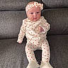 baby, infant, child, headband, heart_pattern, outfit, clothing, sitting, couch, sofa, furniture, indoor, person, footwear, white_shoes, cute, portrait, expression, texture, home