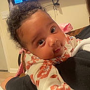 Avionna is registered to the contest to win money with this photo: baby, child, portrait, face, curly_hair, indoor, person, clothing, floral_pattern, hand, arm, television, sports, home, couch, blanket, expression, young, cute, closeup