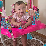 Ava joined the competition — help win amazing prizes! baby, child, smiling, standing, activity_jumper, toy, indoor, carpet, pink, clothing, happy, person, face, play, infant, legs, feet, colorful, home, joy