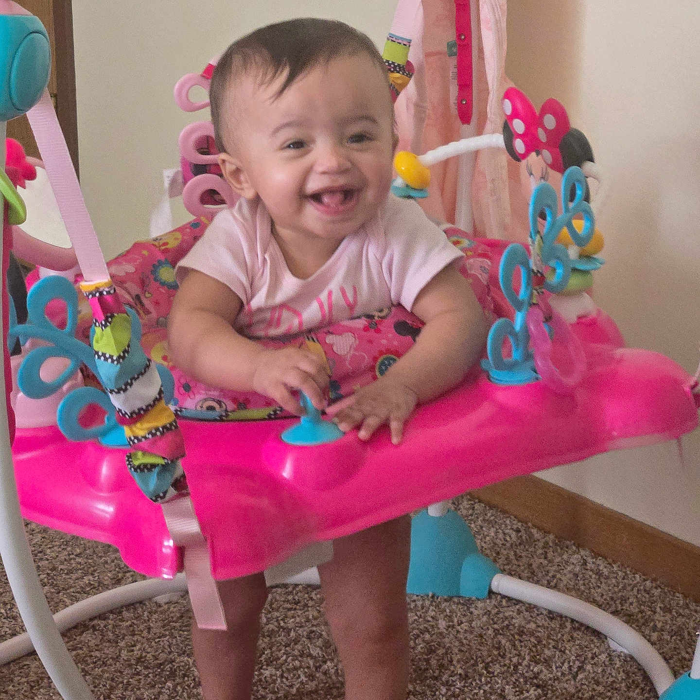 Ava joined the competition — help win amazing prizes! baby, child, smiling, standing, activity_jumper, toy, indoor, carpet, pink, clothing, happy, person, face, play, infant, legs, feet, colorful, home, joy
