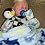 baby, sleeping, pacifier, penguin_plush, blanket, cozy, soft_toy, infant, cute, child, comfort, resting, bedtime, warm, clothing, face, hand, indoor, cuddle, peaceful