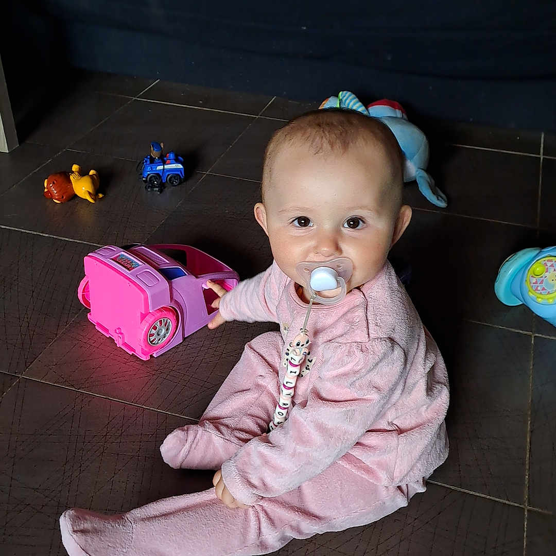 Brice Chretien participe au concours pour gagner de l'argent avec cette photo : baby, beads, child, colorful, comfort, cute, floor, fun, indoor, infant, pacifier, person, pink_outfit, play, sitting, smiling, tiles, toy, toy_car, young_child