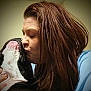 woman, dog, kiss, affection, close_up, indoor, brown_hair, black_and_white_dog, pet, love, face, human, animal, friendship, portrait, emotion, tenderness, person, interaction, cuddle
