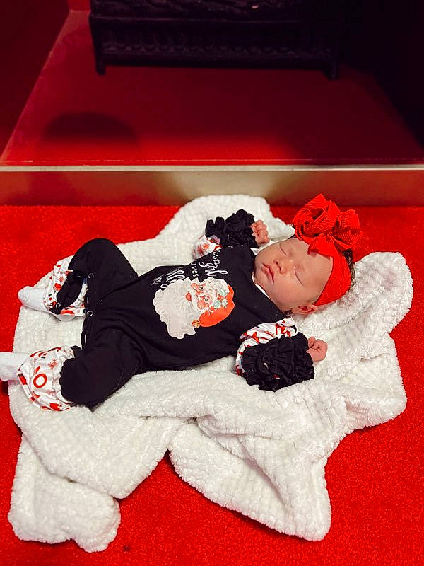 Lilah is registered to the contest to win money with this photo: art, baby_toddler_clothing, carmine, child, comfort, event, fictional_character, font, gesture, happy, headwear, linens, love, pattern, person, petal, red, romance, room, toddler