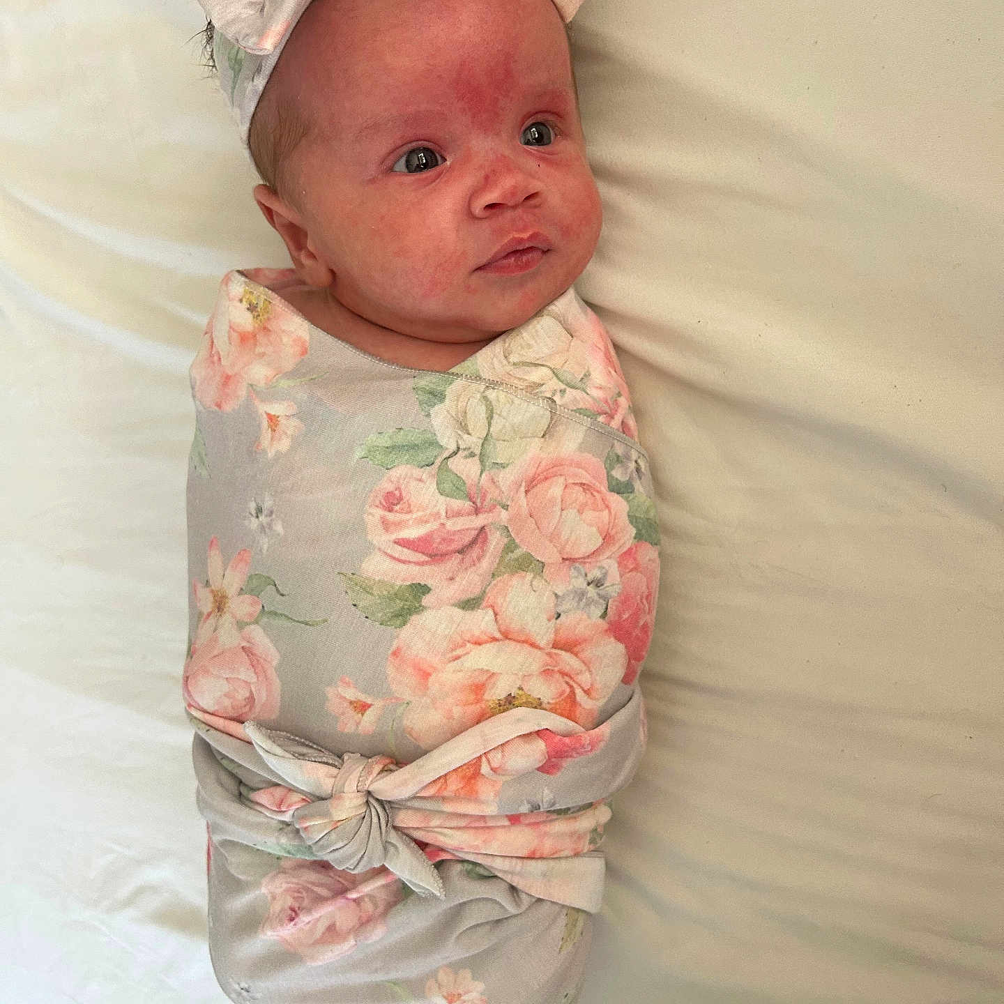 Adelina is registered to the contest to win money with this photo: baby, infant, swaddled, blanket, floral_pattern, headband, bow, lying_down, cute, newborn, face, skin, expression, bed, soft, child, portrait, indoors, sleepwear, resting