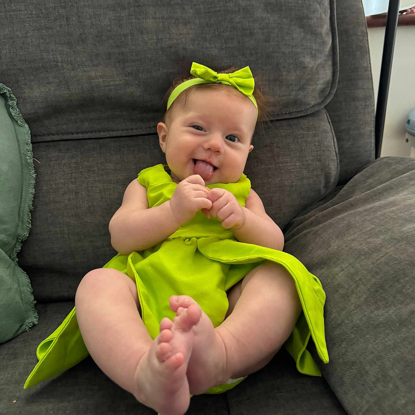 Storey joined the competition — help win amazing prizes! baby, child, couch, cozy, cute, feet, furniture, green_dress, hands, happy, headband, home, indoor, infant, person, playful, portrait, sitting, smiling, tongue_out