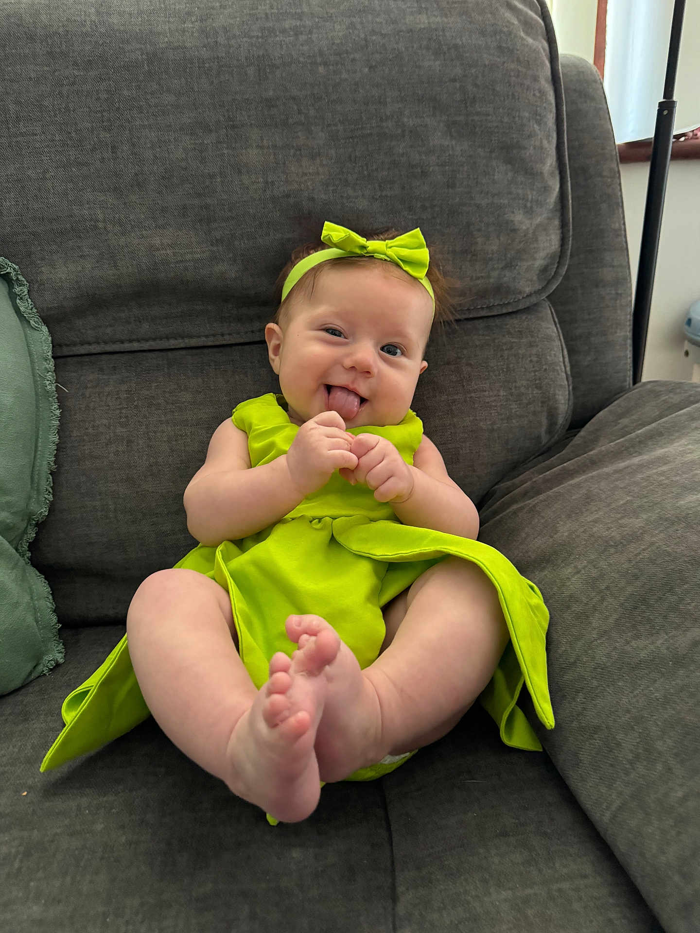 Storey joined the competition — help win amazing prizes! baby, child, smiling, tongue_out, green_dress, headband, sitting, couch, indoor, playful, happy, infant, cute, feet, hands, person, furniture, portrait, cozy, home