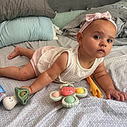 Faith Isabella joined the competition — help win amazing prizes! baby, infant, child, bed, pillow, blanket, toy, headband, bow, tummy_time, curious, indoors, soft_lighting, sleeping_area, clothing, person, skin, face, expression, playtime