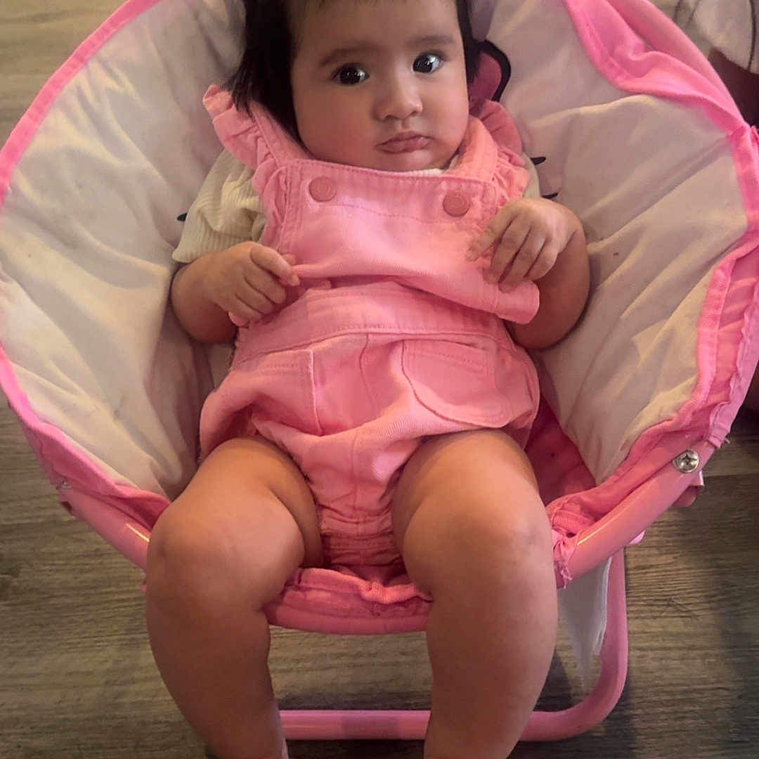 Adianney joined the competition — help win amazing prizes! baby, chair, child, clothing, cute, expression, feet, floor, furniture, hair, indoor, infant, legs, person, pigtails, pink, portrait, room, seated, wood_floor