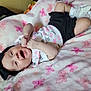Coco is registered to the contest to win money with this photo: baby, infant, headband, black_bow, blanket, pink, butterfly_pattern, smile, happy, lying_down, white_shoes, socks, clothing, cute, child, soft_texture, indoors, cozy, portrait, baby_girl