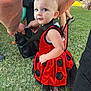 toddler, child, costume, ladybug, red_dress, black_spots, outdoor, grass, people, arms, legs, shoes, sandals, curious, blue_eyes, short_hair, cute, festive, portrait, daytime