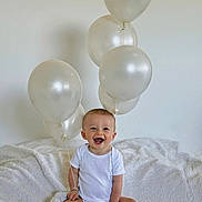 Solann a rejoint le concours — aidez-le/la à gagner de superbes lots ! baby, balloons, blanket, celebration, child, clothing, cute, fun, happy, indoor, infant, joyful, minimalist, one_person, portrait, sitting, smiling, soft_texture, toddler, white