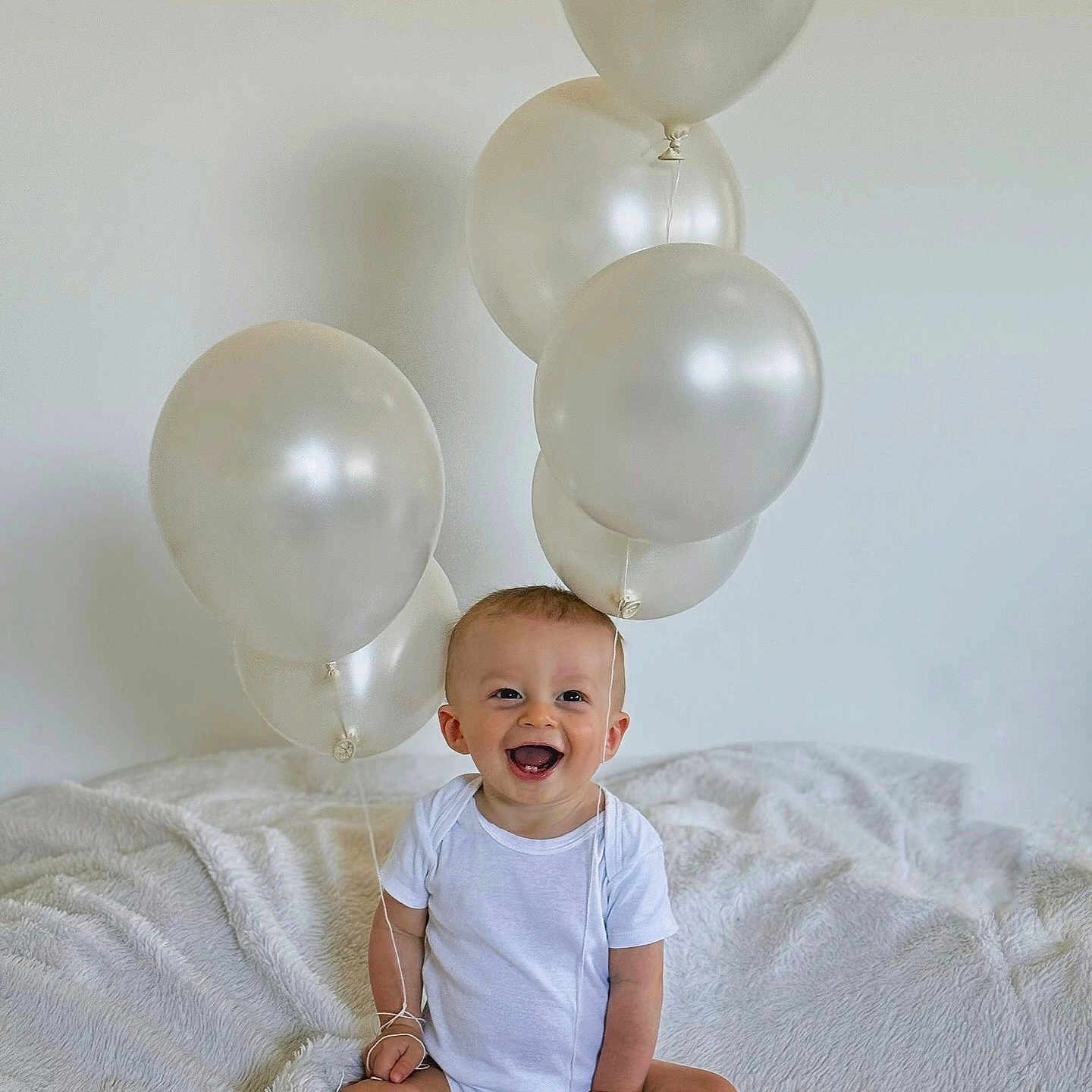 Solann a rejoint le concours — aidez-le/la à gagner de superbes lots ! baby, balloons, blanket, celebration, child, clothing, cute, fun, happy, indoor, infant, joyful, minimalist, one_person, portrait, sitting, smiling, soft_texture, toddler, white