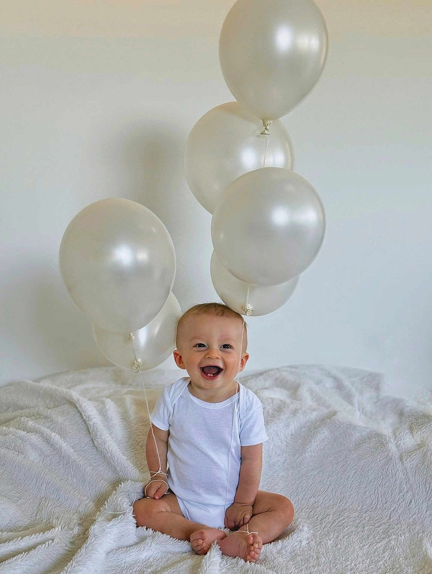 Solann a rejoint le concours — aidez-le/la à gagner de superbes lots ! baby, balloons, blanket, celebration, child, clothing, cute, fun, happy, indoor, infant, joyful, minimalist, one_person, portrait, sitting, smiling, soft_texture, toddler, white