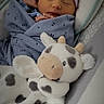 newborn, baby, sleeping, infant, child, face, portrait, blanket, swaddle, hat, striped_hat, plush_toy, cow_toy, stuffed_animal, car_seat, cozy, indoors, peaceful, soft_toys, closeup