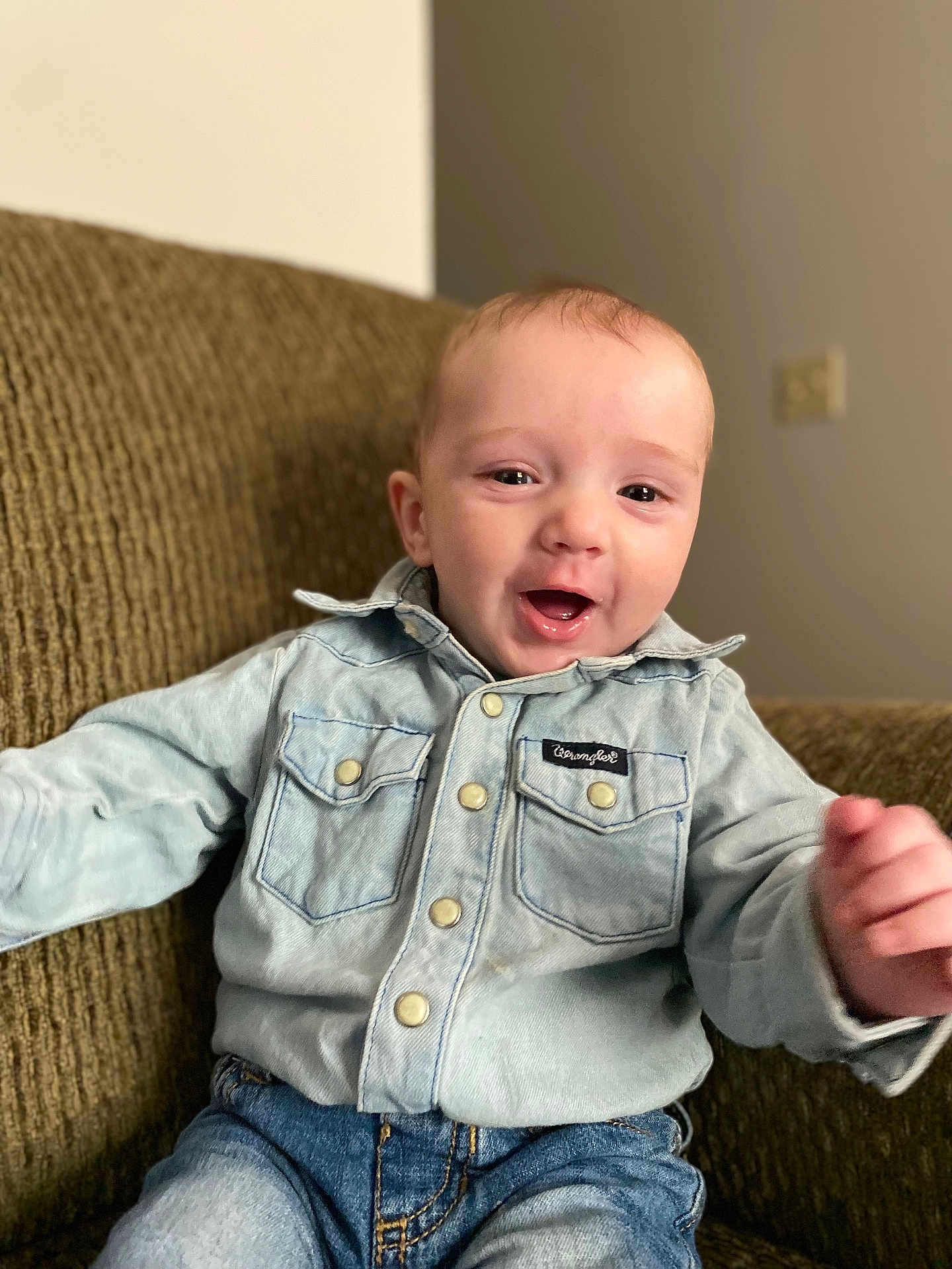 Luca is registered to the contest to win money with this photo: baby, buttoned_shirt, casual_clothing, child, comfortable, couch, cute, denim_shirt, face, happy, home, indoor, jeans, person, portrait, seated, short_hair, smiling, toddler, young_child