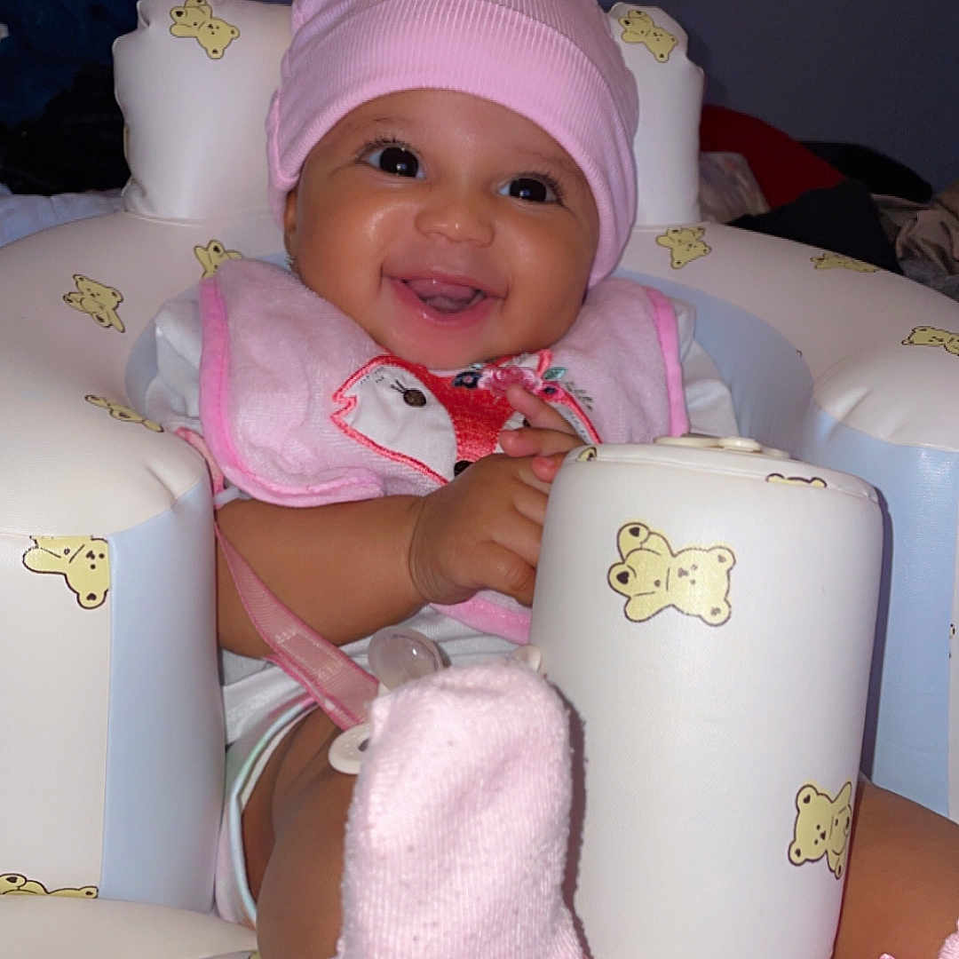 Xylie joined the competition — help win amazing prizes! baby, baby_girl, child, childhood, closeup, cute, footwear, happy, indoor, infant, inflatable_seat, pink_bib, pink_hat, playful, portrait, seat, smiling, sock, soft_lighting, teddy_bear_pattern