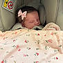 baby, sleeping, car_seat, pink_bow, blanket, floral_pattern, infant, child, cute, peaceful, soft, head, face, hair, indoors, safety, rest, comfort, newborn, bundle