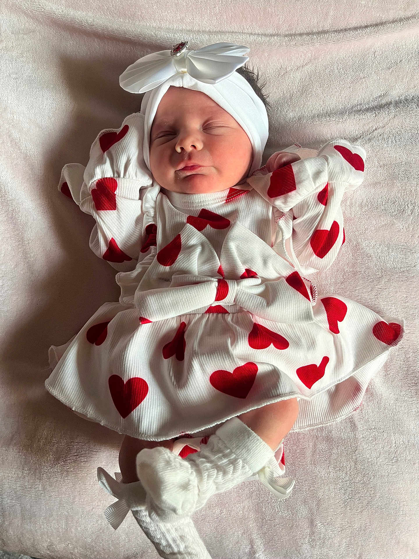 Lottie-Lil is registered to the contest to win money with this photo: baby, newborn, sleeping, white_headband, red_hearts, dress, bow, socks, blanket, soft_lighting, infant, cute, adorable, cozy, portrait, clothing, face, peaceful, hands_up, lying_down