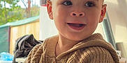 Kaïs a rejoint le concours — aidez-le/la à gagner de superbes lots ! child, toddler, smiling, knitted_sweater, brown_sweater, indoor, natural_light, window, face, portrait, happy, cute, young_child, buttoned_sweater, short_hair, person, casual, cozy, curious, baby