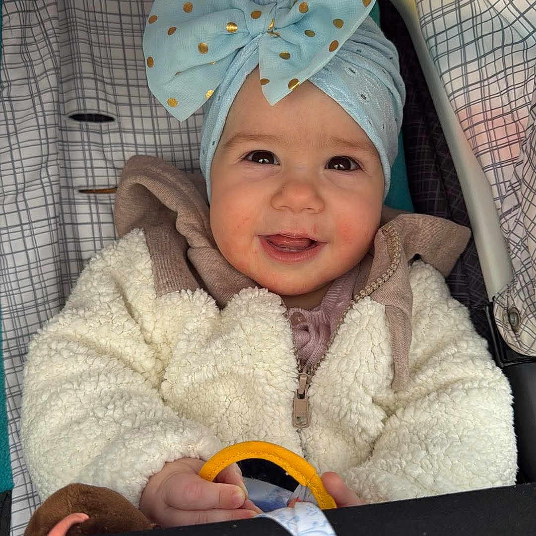 Eva is registered to the contest to win money with this photo: accessories, baby, cap, clothing, coat, face, furniture, happy, hat, head, homedecor, jacket, knitwear, laughing, person, photography, portrait, smile, sweater, tape