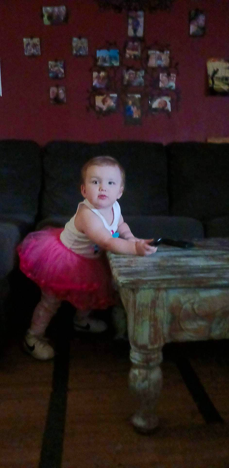 Hensley is registered to the contest to win money with this photo: baby, baby_toddler_clothing, child, couch, event, floor, flooring, fun, hardwood, human_body, human_leg, leg, living_room, magenta, person, pink, room, sitting, table, toddler
