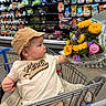 Andre joined the competition — help win amazing prizes! baby, child, shopping_cart, hat, flowers, sunflowers, grocery_store, produce, tshirt, beige, purple_flowers, curious, infant, clothing, sitting, shopping, retail, aisle, bouquet, cute