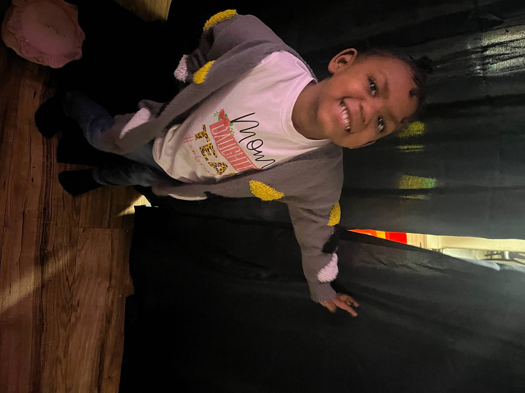 Brianna is registered to the contest to win money with this photo: child, elbow, event, flash_photography, flooring, fun, hardwood, joy, knee, night, outdoor_shoe, person, personal_protective_equipment, room, sitting, smile, sportswear, t_shirt, toddler, wood