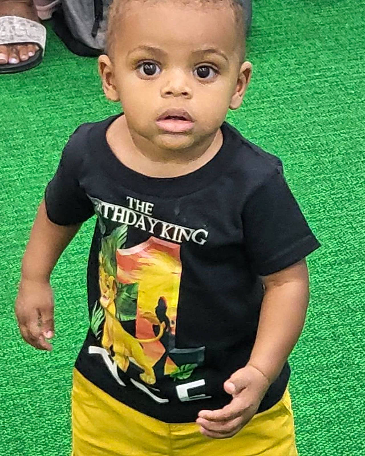 Ace is registered to the contest to win money with this photo: active_shirt, baby, baby_toddler_clothing, cheek, child, cool, face, fun, grass, green, hairstyle, happy, head, nose, pattern, person, skin, sleeve, t_shirt, toddler