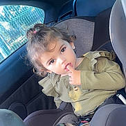 Antonia participe au concours pour gagner de l'argent avec cette photo : toddler, child, car_seat, car_interior, window, green_clothing, camouflage_pants, black_shoes, finger_in_mouth, curly_hair, topknot, seatbelt, sitting, daylight, casual_clothing, young_child, portrait, seat, person, indoors