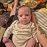 Brooklynn joined the competition — help win amazing prizes! baby, infant, person, clothing, hand, leg, tattoo, blanket, food_container, snack_bag, couch, room, indoor, casual, sitting, wide_eyes, curious, skin, foot, relaxed