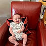 Henry joined the competition — help win amazing prizes! baby, child, smiling, armchair, red_leather, cushion, indoor, happy, infant, person, sitting, cute, comfortable, clothing, patterned, face, legs, feet, home, furniture