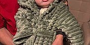 Henry is registered to the contest to win money with this photo: adult_hand, baby, child, closeup, costume, couch, cute, dinosaur_costume, expression, furniture, holding, hood, indoor, person, plush, portrait, pout, red_shirt, soft_texture, tattoo
