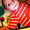 Avery joined the competition — help win amazing prizes! baby, child, striped_clothing, red_clothing, blanket, colorful_pattern, face, eyes, infant, lying_down, indoor, looking_at_camera, curious, serious_expression, young_child, head, skin, photography, portrait, baby_toy