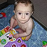 Avery is registered to the contest to win money with this photo: baby, child, toy, playpen, colorful, indoors, curious, sitting, infant, plastic_toy, floor, looking_up, cute, young_child, play, patterned_mat, person, expression, naked, development
