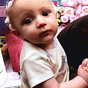 Avery is registered to the contest to win money with this photo: baby, background, blue, child, clothing, cute, expression, face, hands, indoor, infant, looking, person, pink, plush_toys, portrait, short_sleeve, stuffed_animals, yellow, young