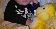 Avery joined the competition — help win amazing prizes! baby, sleeping, plush_toy, blanket, child, skeleton_outfit, teddy_bear, yellow, cuddling, indoors, bed, cute, peaceful, soft_toys, infant, face, person, resting, comfort, nap