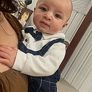 Legend is registered to the contest to win money with this photo: baby, child, infant, person, clothing, bow_tie, indoor, portrait, face, holding, adult, curious, fashion, cute, young, skin, head, hand, background, photo_frame