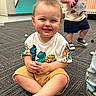 toddler, child, smiling, sitting, indoor, carpet, toy, shorts, tshirt, play, daycare, happy, person, floor, cute, young_child, kids, background, expression, casual_clothing