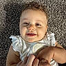 Nevaeh is registered to the contest to win money with this photo: baby, child, smile, curly_hair, carpet, hand, holding, white_clothing, infant, cute, happy, person, skin, closeup, indoors, portrait, young, toddler, expression, candid