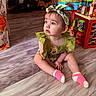 baby, blanket, child, colorful, curious, cute, decor, floor, furniture, green_clothing, headband, indoor, person, playroom, sitting, socks, toddler, toys, wooden_floor, young_child