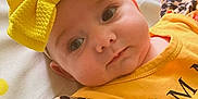 Maisey is registered to the contest to win money with this photo: adorable, apparel, baby, blanket, child, closeup, cute, expression, face, floral_pattern, headband, headwear, indoors, infant, lying_down, outfit, portrait, soft_lighting, yellow_bow, young_child