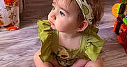 Maisey is registered to the contest to win money with this photo: baby, child, colorful, curtain, cute, expression, floor, green_dress, hair_bow, headband, home, indoor, person, pink_socks, playful, portrait, sitting, toddler, toy, wooden_floor