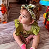 baby, child, colorful, curtain, cute, expression, floor, green_dress, hair_bow, headband, home, indoor, person, pink_socks, playful, portrait, sitting, toddler, toy, wooden_floor