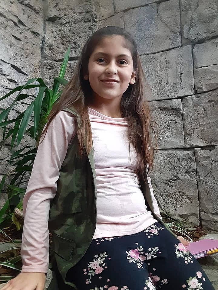 Daniella is registered to the contest to win money with this photo: beauty, child_model, fawn, jacket, joy, long_hair, person, photo_shoot, photography, plant, shorts, sitting, smile